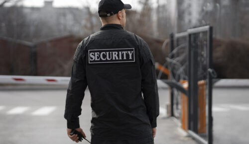 portrait-male-security-guard-with-barbed-wire-fence portrait-male-security-guard-with-barbed-wire-fence